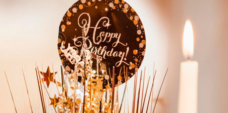 Schild "Happy Birtday" mit Deko und Kerze - bestimmt auch mit einer Rede zum Geburtstag.